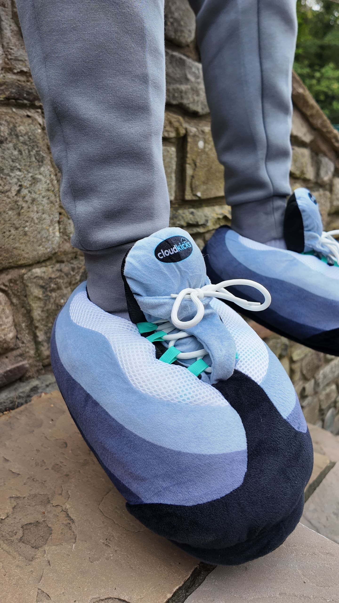 Close-up of Hyper Turquoise CloudKicks on a sandstone step, turquoise lace loops showing